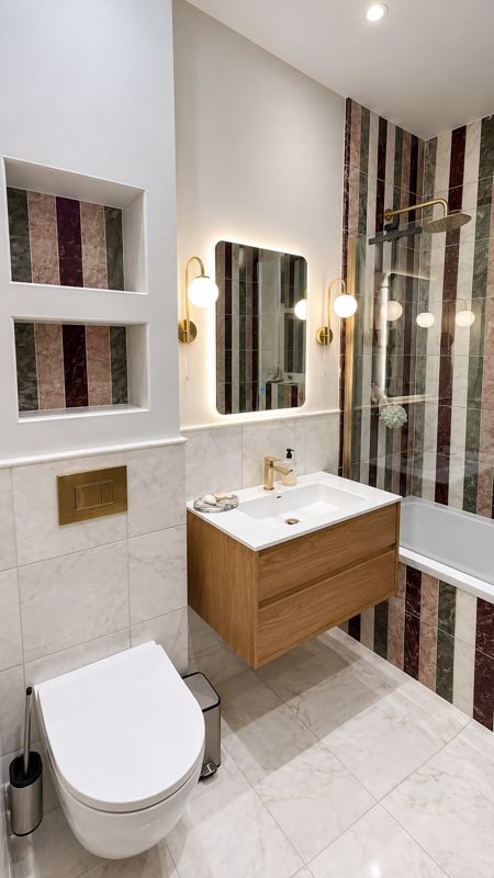 Bathroom with striped marble wall tiles, oak vanity, brass fittings and recessed niches