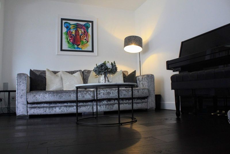 Lounge with grey velvet sofa, tiger artwork and dark wood floor
