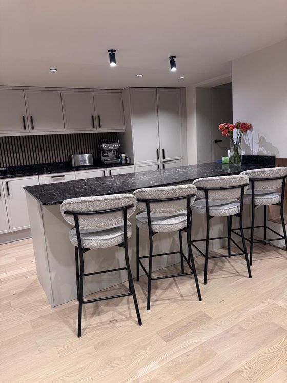 Grey shaker kitchen island with black granite worktop and four bar stools